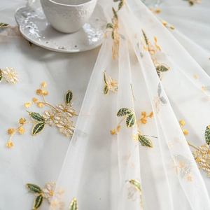 Elegant white tulle tablecloth with yellow flower embroidery and greenery for decor