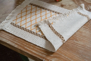 Close-up of cotton linen table runner with orange diamond pattern and fringe details