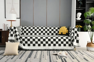 Detail einer karierten Decke mit Fransen auf einem modernen Sofa im Wohnzimmer