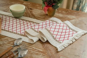 Detail of waffled cotton table runner with red diamond embroidery and white tassels