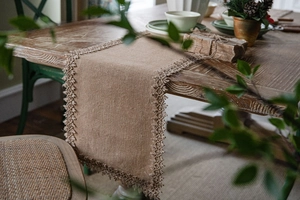 Close-up of natural jute table runner with lace trim on a vintage wooden table
