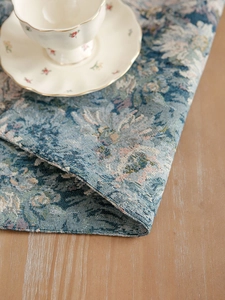 Detail of blue floral jacquard placemat with premium cotton linen texture and hemmed edges