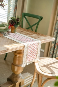 Detail of hand-woven cotton table runner with red diamond embroidery and fringe