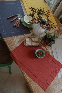 Detailed close-up of plain washed cotton placemats with fringe and decorative stitching