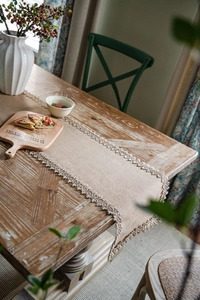 Close-up of natural jute table runner with beige crochet lace on vintage wooden table