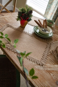 Macro detail of natural jute table runner with delicate lace embroidery for rustic decor