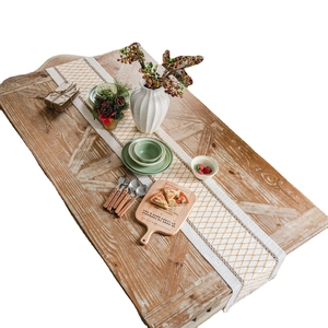 Linen table runner with orange diamond embroidery and decorative tassels on wood table