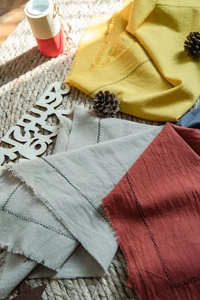 Close-up of washed cotton placemats with frayed edges and decorative black stitching