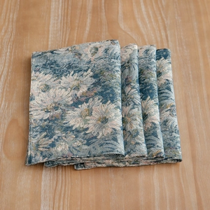 Set of four blue floral jacquard placemats in vintage style on a wooden table