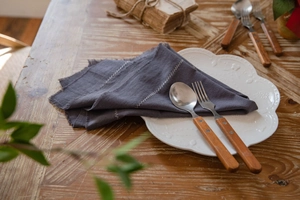 Detail of dark grey washed cotton placemat with white wavy stitching on a ceramic plate