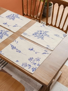 Detailed texture of cotton linen placemats with blue floral sketch prints on wood table