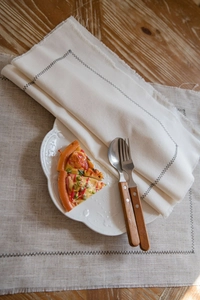 Detailed texture of cotton linen placemat with black zigzag stitching and tassel fringe