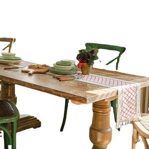 Cotton linen table runner with red diamond embroidery and tassels on wooden table