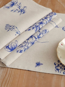 Detail of blue floral cotton linen placemat with vintage bee print on wooden table
