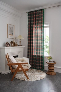 Detail of red and green plaid curtain with emerald green pom-pom fringe decoration