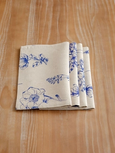 Close-up of blue floral print on linen table mats set against a wooden surface