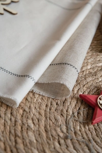 Close-up of cream and linen napkins with black zigzag stitching and raw frayed edges