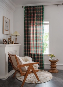 Detail of red and green plaid curtains with elegant fringe trim in a retro living room