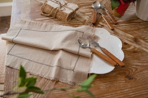 Close-up of linen-textured cotton placemat with frayed edges and stitched rectangle pattern