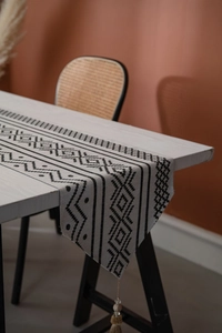 Détail macro du chemin de table jacquard géométrique avec glands bohèmes et perles