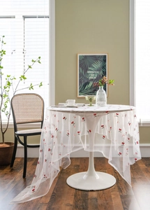 Close-up of white mesh tablecloth featuring delicate red cherry embroidery and green leaves