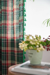 Detail of green plaid curtains with decorative dark green fringe tassels in cotton linen fabric