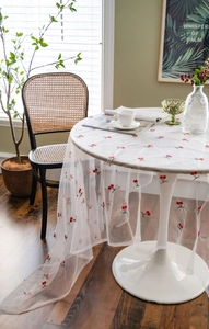 Close-up of white mesh tablecloth featuring delicate red cherry embroidery details