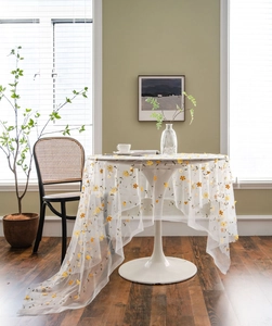 Detail of white lace tablecloth with delicate yellow and orange floral embroidery