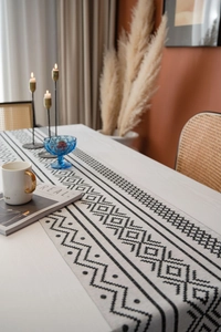 Détail d'un chemin de table bohème avec motifs géométriques noirs sur tissu en lin