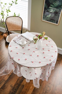 Detail of white mesh tablecloth with red cherry embroidery on a marble table