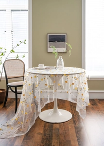 Detail of yellow flower embroidery on white sheer lace tablecloth for photo props