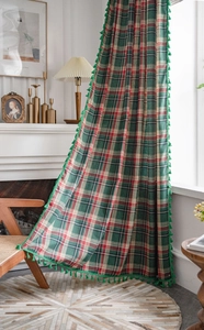 Detailed view of red and green plaid curtain with green tassel edge in vintage style