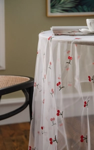 Detail of white mesh tablecloth with red cherry embroidery for photography background