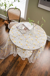 Close-up of sheer white mesh tablecloth with delicate yellow floral embroidery details
