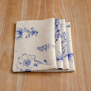 Set of 4 blue sketch floral cotton linen placemats neatly folded on a wooden table