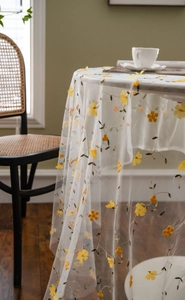 Detailed view of white floral lace tablecloth with yellow embroidery for photography