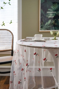 Detail of white mesh tablecloth with delicate red cherry embroidery in vintage French style
