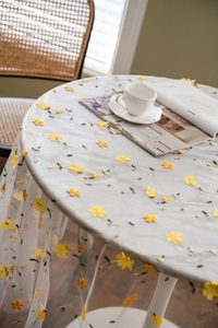 Close-up of white lace tablecloth with yellow floral embroidery and green vine details