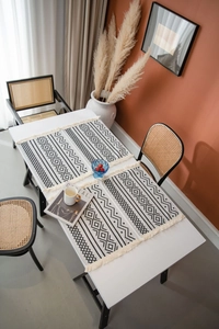 Détail de set de table bohème avec motifs géométriques noir et blanc et pompons fins