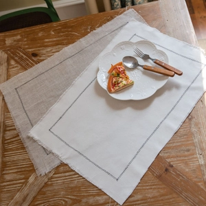 Fringed washed cotton placemat set on wooden table with elegant white ceramic plate