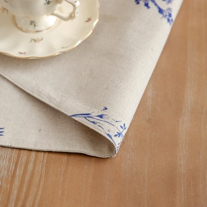 Linen placemat with blue floral sketches on a beige background in a rustic table setting