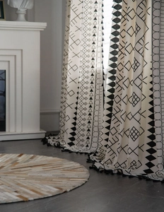 Detail of bohemian cotton linen curtain featuring black geometric patterns and fringe