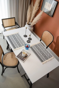 Détail du chemin de table jacquard géométrique avec motifs noirs et blancs et petits pompons
