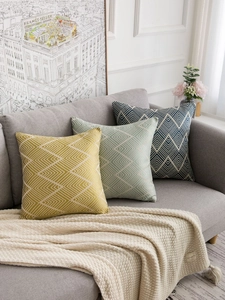 Close-up of geometric V-pattern jacquard pillow covers in ginger, green, and navy colors
