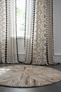 Close-up of bohemian cotton linen curtain with black geometric patterns and tassels
