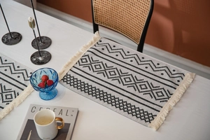 Détail d'un chemin de table bohème avec motifs géométriques noirs et franges