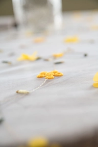 Detailed embroidery of yellow flowers on white lace mesh fabric for table decoration