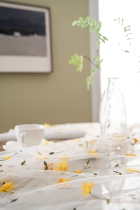 Detail of white lace fabric with yellow flower embroidery and green leaf patterns