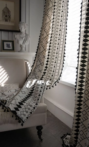 Detail of bohemian cotton linen curtain with black geometric prints and fringe trim