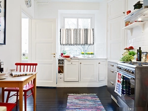 Détail du rideau de cuisine blanc avec motifs géométriques noirs et pompons